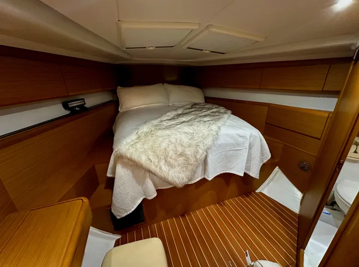 Star IV Yacht Photos Pics Cozy cabin interior of 2010 Jeanneau Sun Odyssey 50 DS with wooden finish and comfortable bedding.