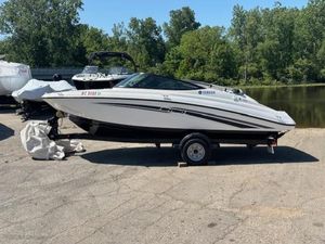 2017 Yamaha SX190 boat on trailer, parked near a lake with trees in the background.