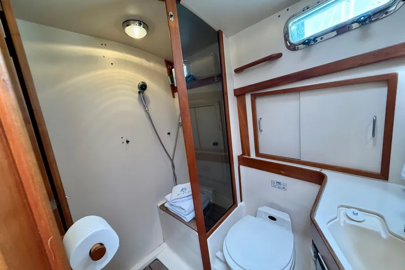 Daystar Yacht Photos Pics 2001 Sabre Sabreline 34 yacht bathroom with shower, toilet, and wooden cabinetry.
