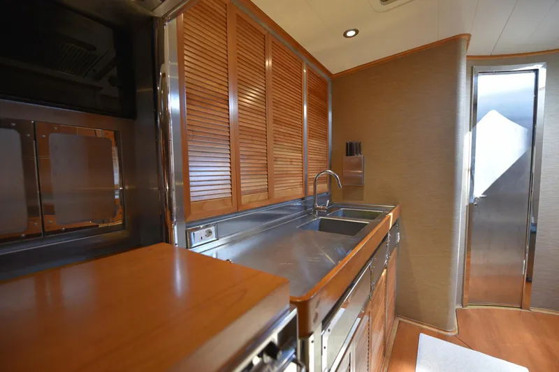 Green Eyes Yacht Photos Pics Luxurious kitchen interior of 2001 Wally Full Displacement Sailing Yacht with wooden cabinets and stainless steel sink.