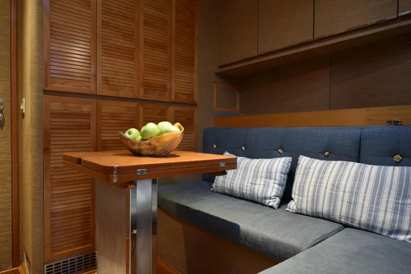 Green Eyes Yacht Photos Pics Cozy interior of 2001 Wally sailing yacht with wooden table and cushioned seating.