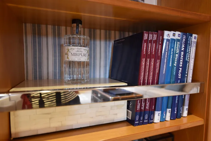 Green Eyes Yacht Photos Pics Shelf with Mirpuri gin bottle and nautical books on a 2001 Wally sailing yacht.