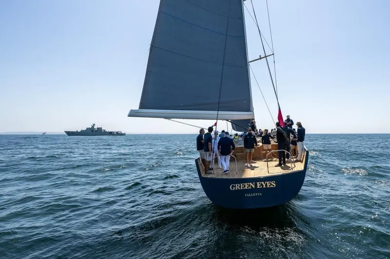Green Eyes Yacht Photos Pics Wally 2001 sailing yacht "Green Eyes" with crew on open sea, distant ship visible.