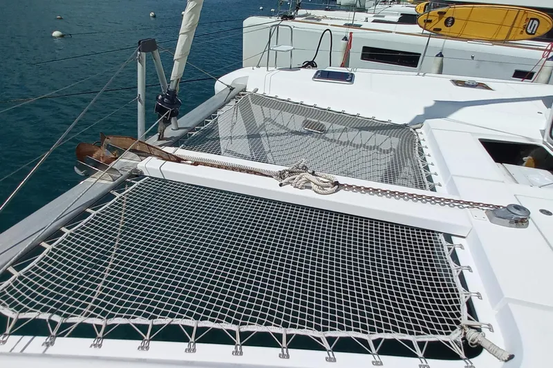 Benetnash II Yacht Photos Pics Catamaran Lagoon 42 (2016) with netted deck, anchored in calm waters.