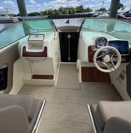  Yacht Photos Pics 2023 Chris-Craft Launch 28 GT interior with steering wheel and dashboard, docked by the water.