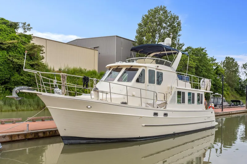 Seabatical Yacht Photos Pics 2008 North Pacific 43 Pilothouse yacht docked on calm water, surrounded by greenery.