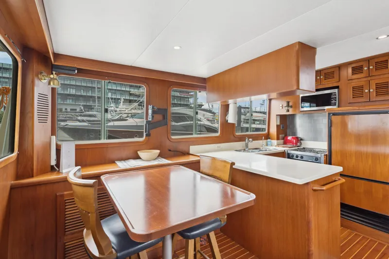 Seabatical Yacht Photos Pics Interior of 2008 North Pacific 43 Pilothouse yacht with wooden dining area and kitchen.