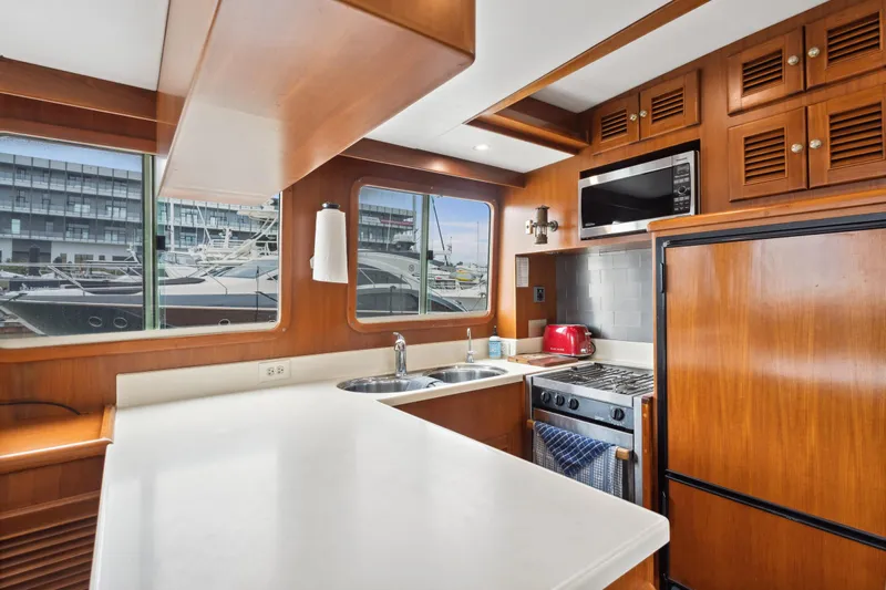 Seabatical Yacht Photos Pics 2008 North Pacific 43 Pilothouse kitchen with wood cabinetry, modern appliances, and marina view.