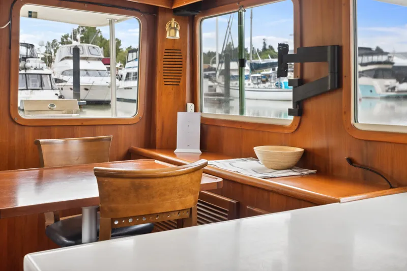 Seabatical Yacht Photos Pics Interior of 2008 North Pacific 43 Pilothouse with wooden dining area and marina view.