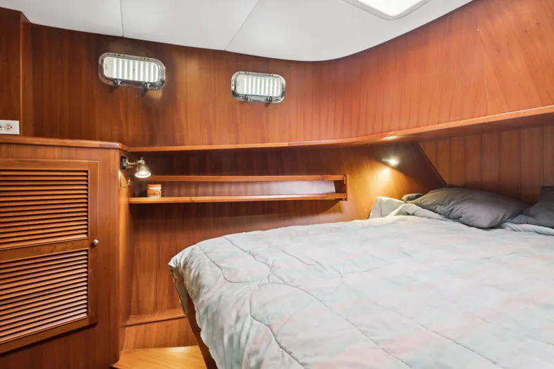 Seabatical Yacht Photos Pics Cozy cabin interior of 2008 North Pacific 43 Pilothouse with wooden paneling and bed.
