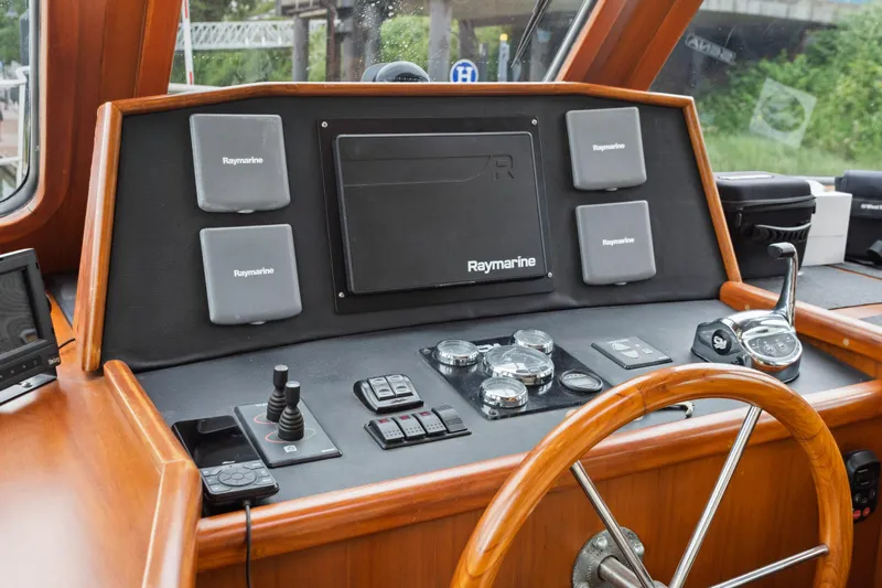 Seabatical Yacht Photos Pics Pilothouse of 2008 North Pacific 43, featuring Raymarine navigation equipment and wooden steering wheel.