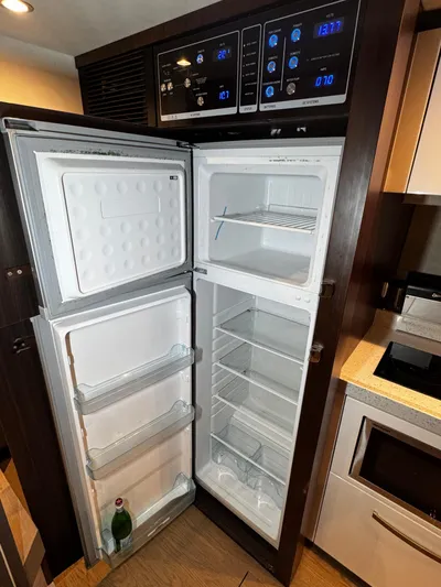  Yacht Photos Pics Open refrigerator in 2018 Fairline Targa 48 Open yacht kitchen, showing empty shelves and a bottle.