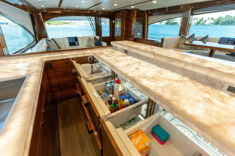 Team Harvey Yacht Photos Pics Luxurious interior of 2026 Viking 82 Convertible yacht with open kitchen drawers and scenic ocean view.