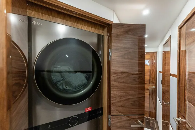 Team Harvey Yacht Photos Pics Laundry area with LG washer in 2026 Viking 82 Convertible yacht, featuring elegant wood paneling.