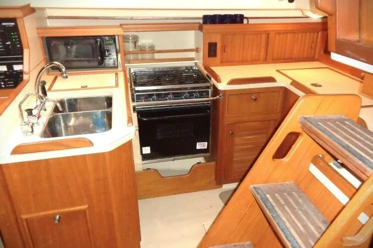Epithelios Yacht Photos Pics Island Packet 420 yacht kitchen interior with wooden cabinetry, stove, sink, and microwave, 2002 model.