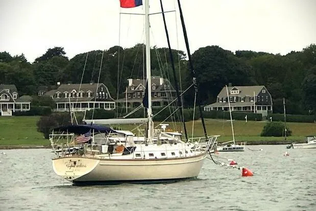 Epithelios Yacht Photos Pics 2002 Island Packet 420 sailboat anchored near shoreline with houses in the background.