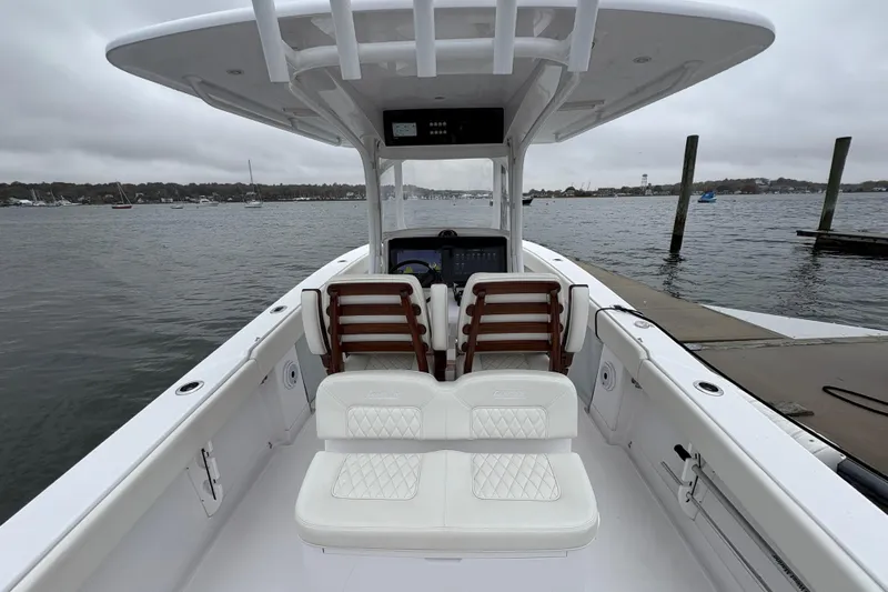 Changes In Lattitudes Yacht Photos Pics 2023 Jupiter 30 boat interior with white seating, docked by a calm waterfront.