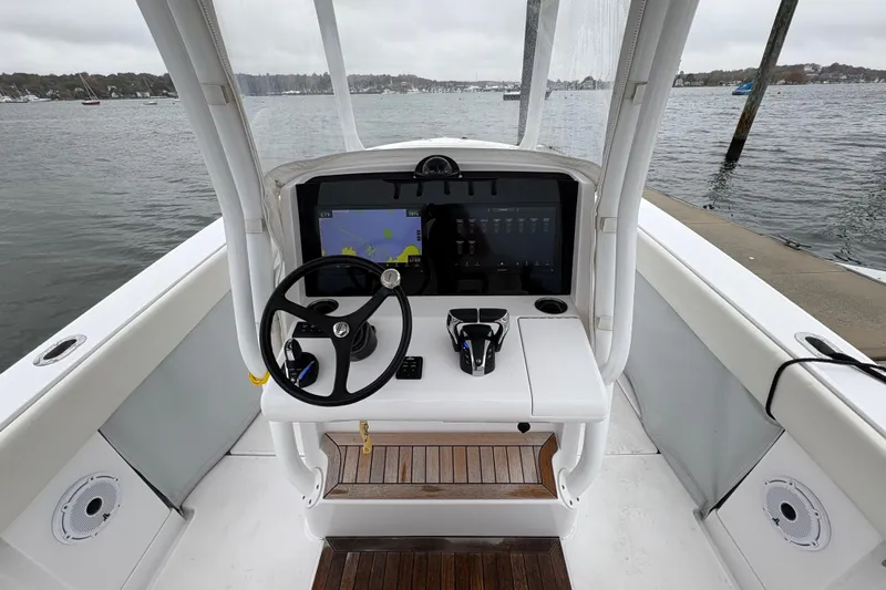 Changes In Lattitudes Yacht Photos Pics 2023 Jupiter 30 boat helm with steering wheel and navigation display on calm water.