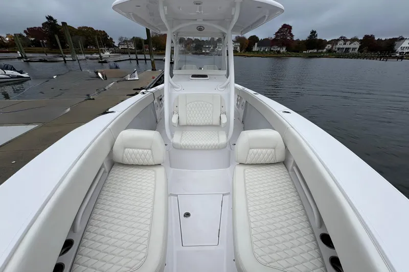 Changes In Lattitudes Yacht Photos Pics 2023 Jupiter 30 boat with white quilted seating, docked by a calm waterfront.