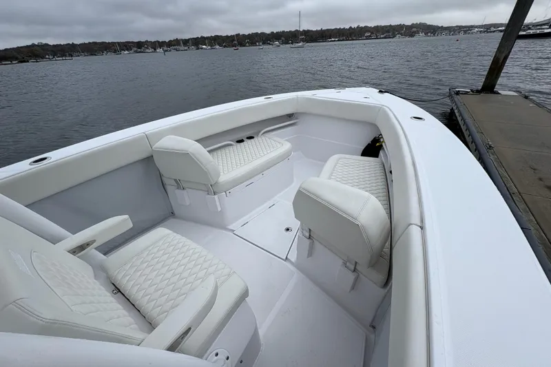 Changes In Lattitudes Yacht Photos Pics 2023 Jupiter 30 boat interior with white seating, docked by a calm waterfront.