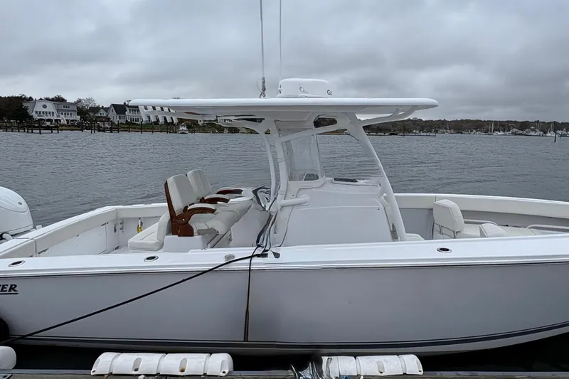 Changes In Lattitudes Yacht Photos Pics 2023 Jupiter 30 boat docked by a calm waterfront under cloudy skies.