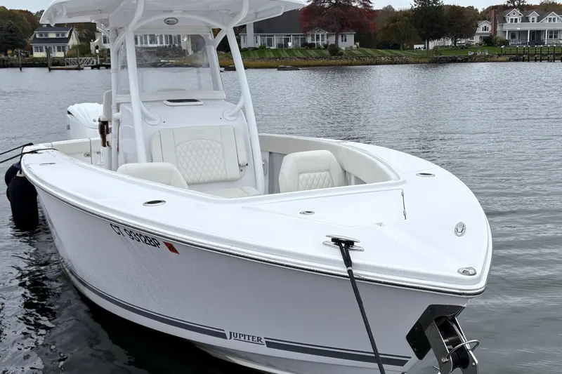 Changes In Lattitudes Yacht Photos Pics 2023 Jupiter 30 boat docked on a serene waterfront with houses in the background.