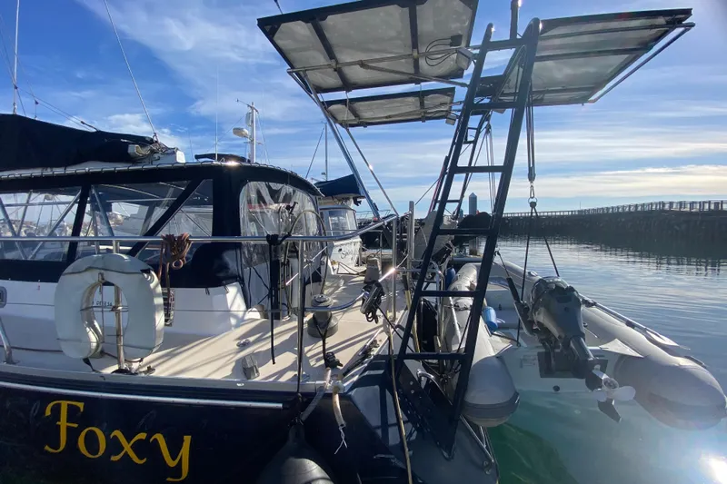Foxy Yacht Photos Pics Sundeer 56 yacht from 1995 docked, featuring solar panels and a dinghy.