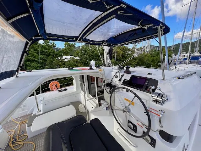 Queen Mary II Yacht Photos Pics 2019 Lagoon 40 catamaran cockpit with steering wheel, navigation controls, and canopy.