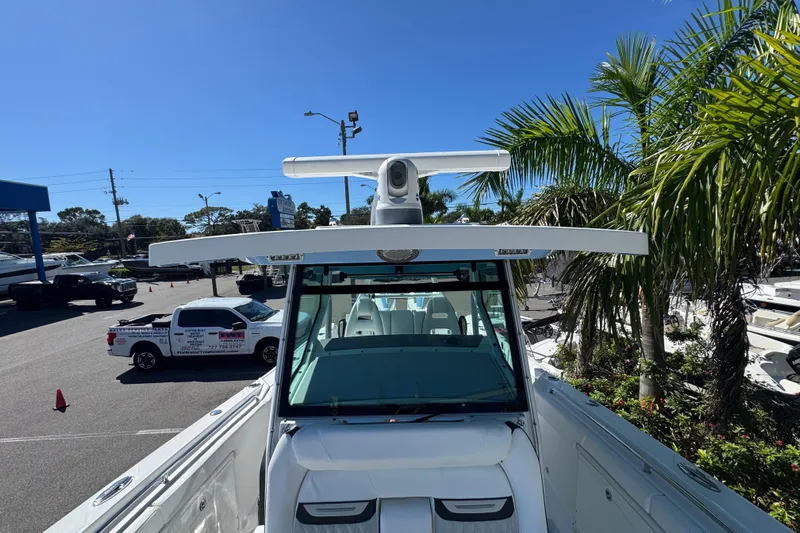  Yacht Photos Pics 2021 Blackfin 332 CC boat with radar, parked near palm trees and vehicles.