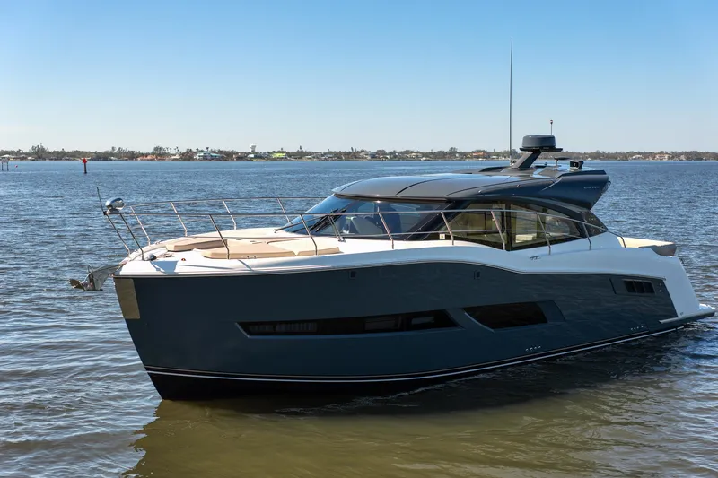 Going Coastal Yacht Photos Pics Luxurious 2019 Carver C43 Coupe yacht cruising on a serene lake under a clear blue sky.