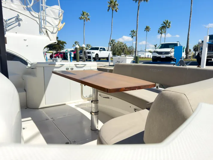 Going Coastal Yacht Photos Pics Luxury yacht deck with seating and table, parked cars, palm trees, and clear blue sky.