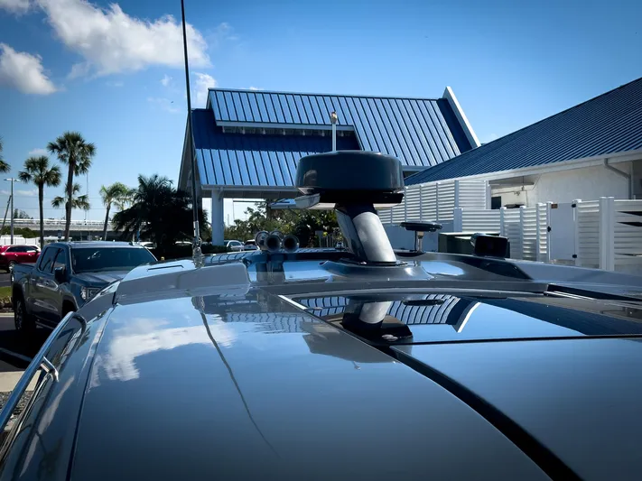 Going Coastal Yacht Photos Pics 2019 Carver C43 Coupe with rooftop equipment, parked near modern buildings and palm trees.