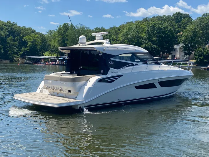  Yacht Photos Pics 2015 Sea Ray 470 Sundancer yacht cruising on a serene lake with lush green surroundings.