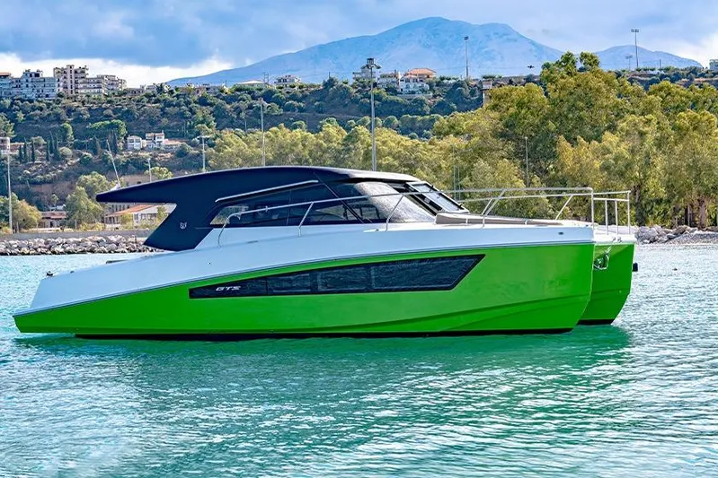  Yacht Photos Pics 2025 Makai M37 boat with sleek design, vibrant green hull, and scenic mountain backdrop.