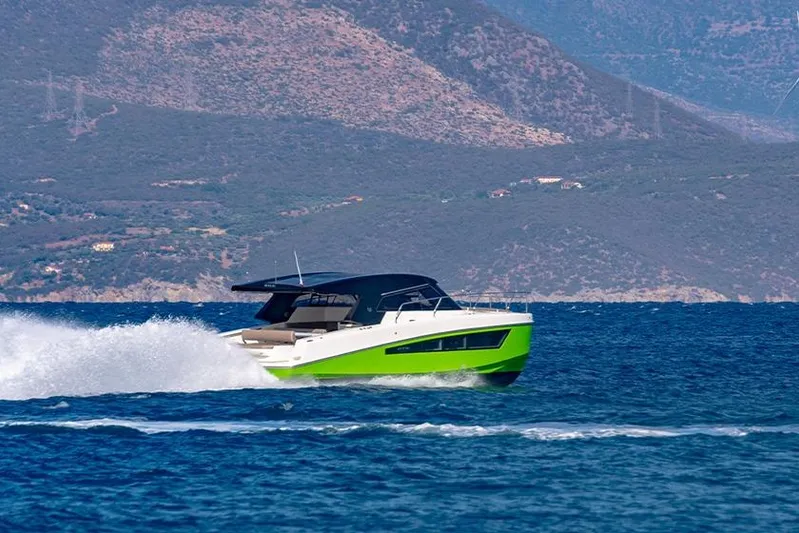  Yacht Photos Pics 2025 Makai M37 boat cruising on blue water with mountainous backdrop.