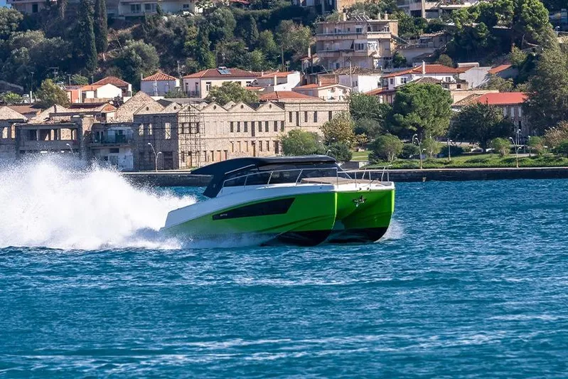  Yacht Photos Pics 2025 Makai M37 boat cruising on blue water near coastal town.