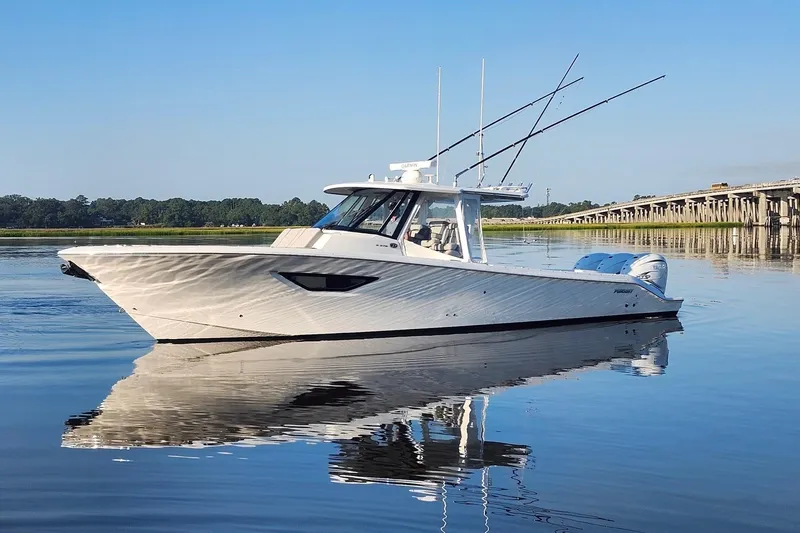  Yacht Photos Pics 2023 Pursuit S 378 Sport boat on calm water near a bridge, clear blue sky.