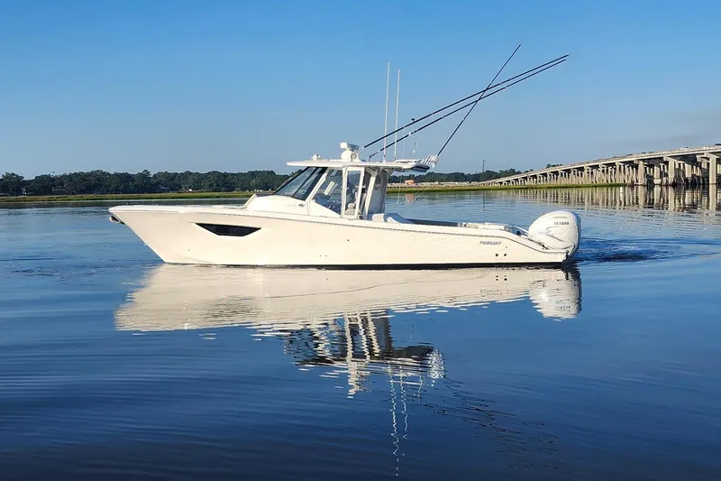  Yacht Photos Pics 2023 Pursuit S 378 Sport boat on calm water, reflecting bridge and clear sky.