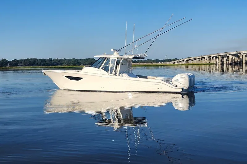  Yacht Photos Pics 2023 Pursuit S 378 Sport boat on calm water near a bridge.