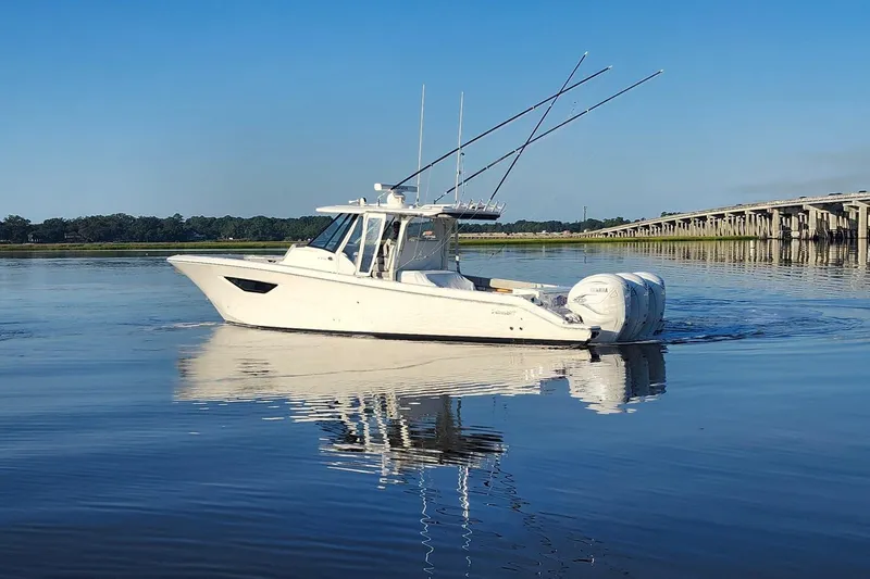  Yacht Photos Pics 2023 Pursuit S 378 Sport boat on calm water near a bridge.