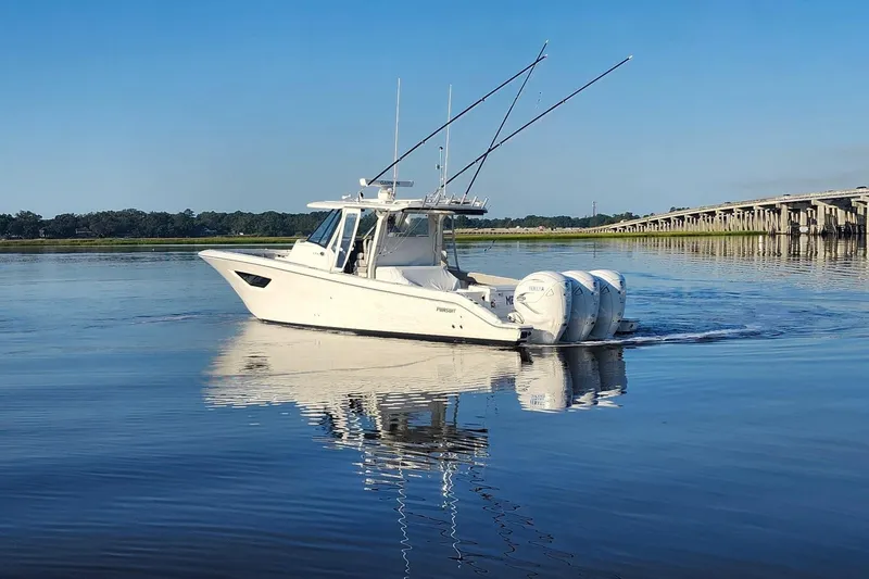  Yacht Photos Pics 2023 Pursuit S 378 Sport boat cruising on calm water near a bridge.