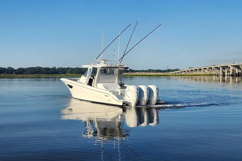 Yacht Photos Pics 2023 Pursuit S 378 Sport boat cruising on calm water near a bridge.