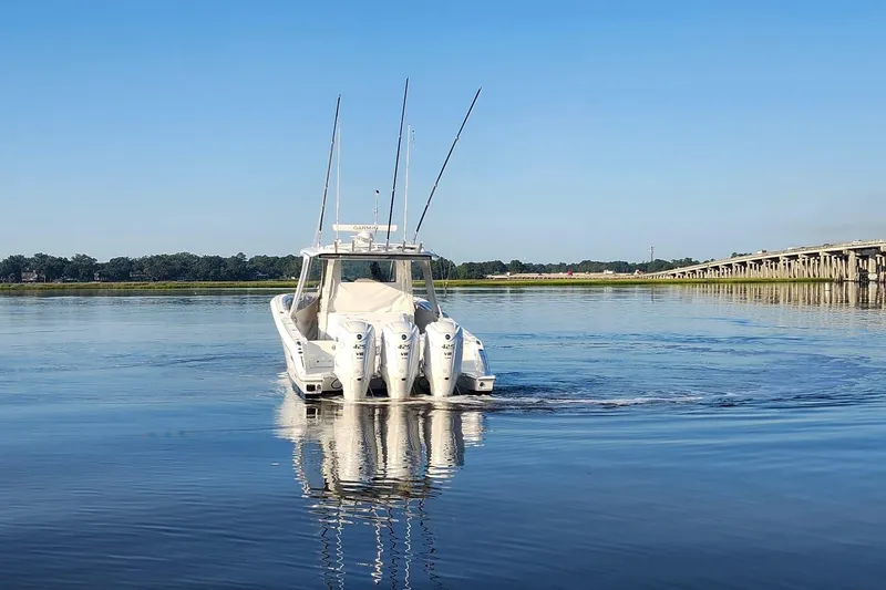  Yacht Photos Pics 2023 Pursuit S 378 Sport boat cruising on calm water near a bridge.