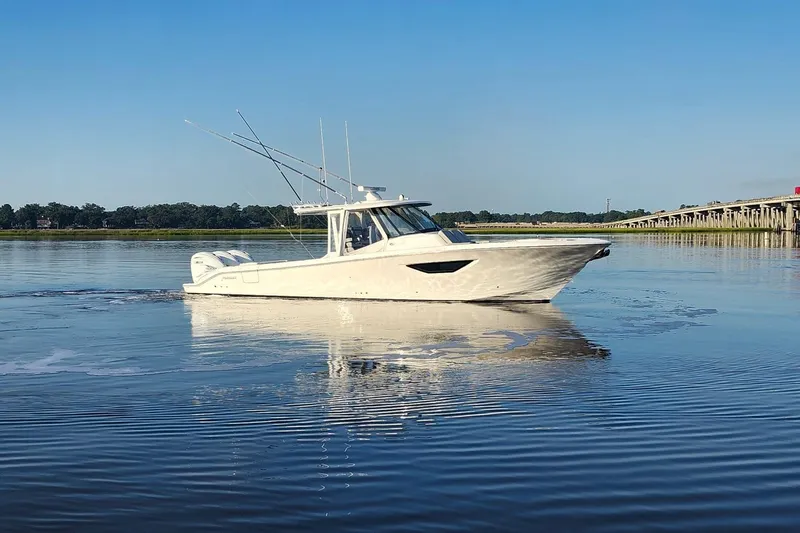  Yacht Photos Pics 2023 Pursuit S 378 Sport boat cruising on calm water near a bridge.