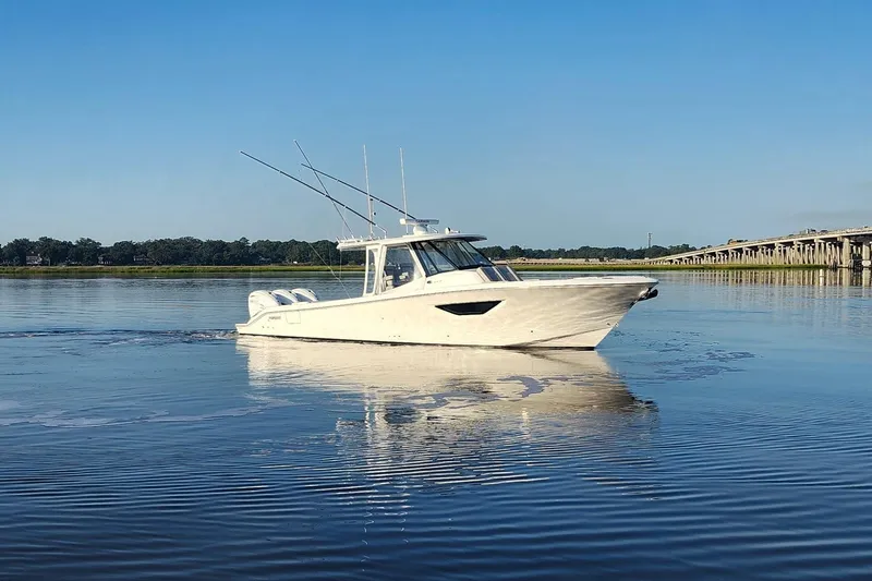  Yacht Photos Pics 2023 Pursuit S 378 Sport boat on calm water near a bridge.