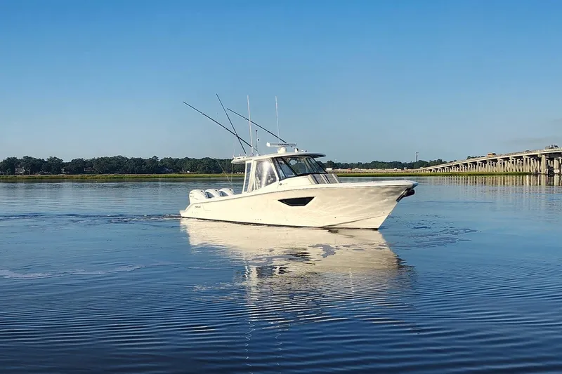  Yacht Photos Pics 2023 Pursuit S 378 Sport boat cruising on calm water near a bridge.
