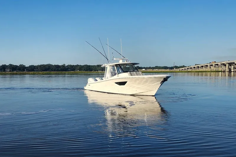  Yacht Photos Pics 2023 Pursuit S 378 Sport boat cruising on calm water near a bridge.