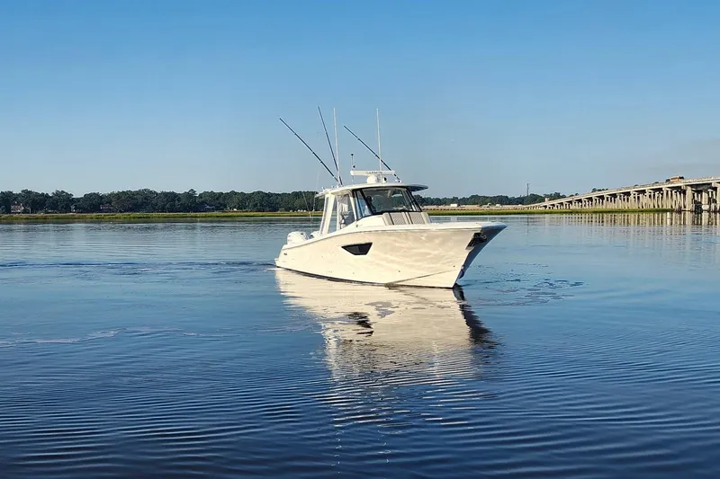  Yacht Photos Pics 2023 Pursuit S 378 Sport boat on calm water near a bridge.
