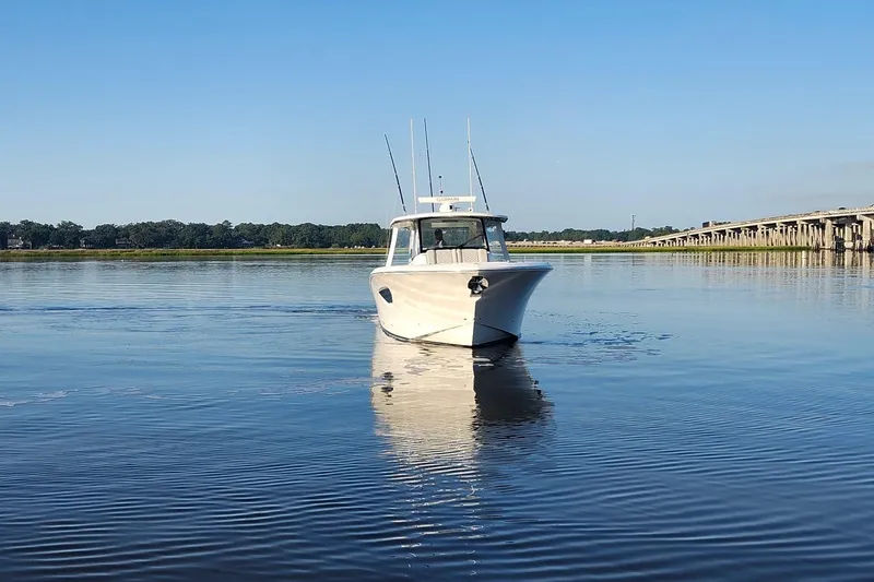  Yacht Photos Pics 2023 Pursuit S 378 Sport boat on calm water near a bridge.