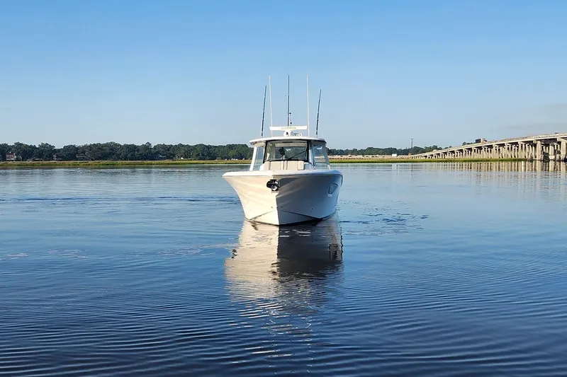  Yacht Photos Pics 2023 Pursuit S 378 Sport boat on calm water near a bridge.